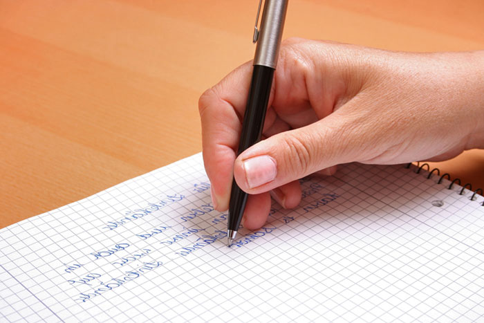 Hand mit Stift beim verfassen eines Briefes